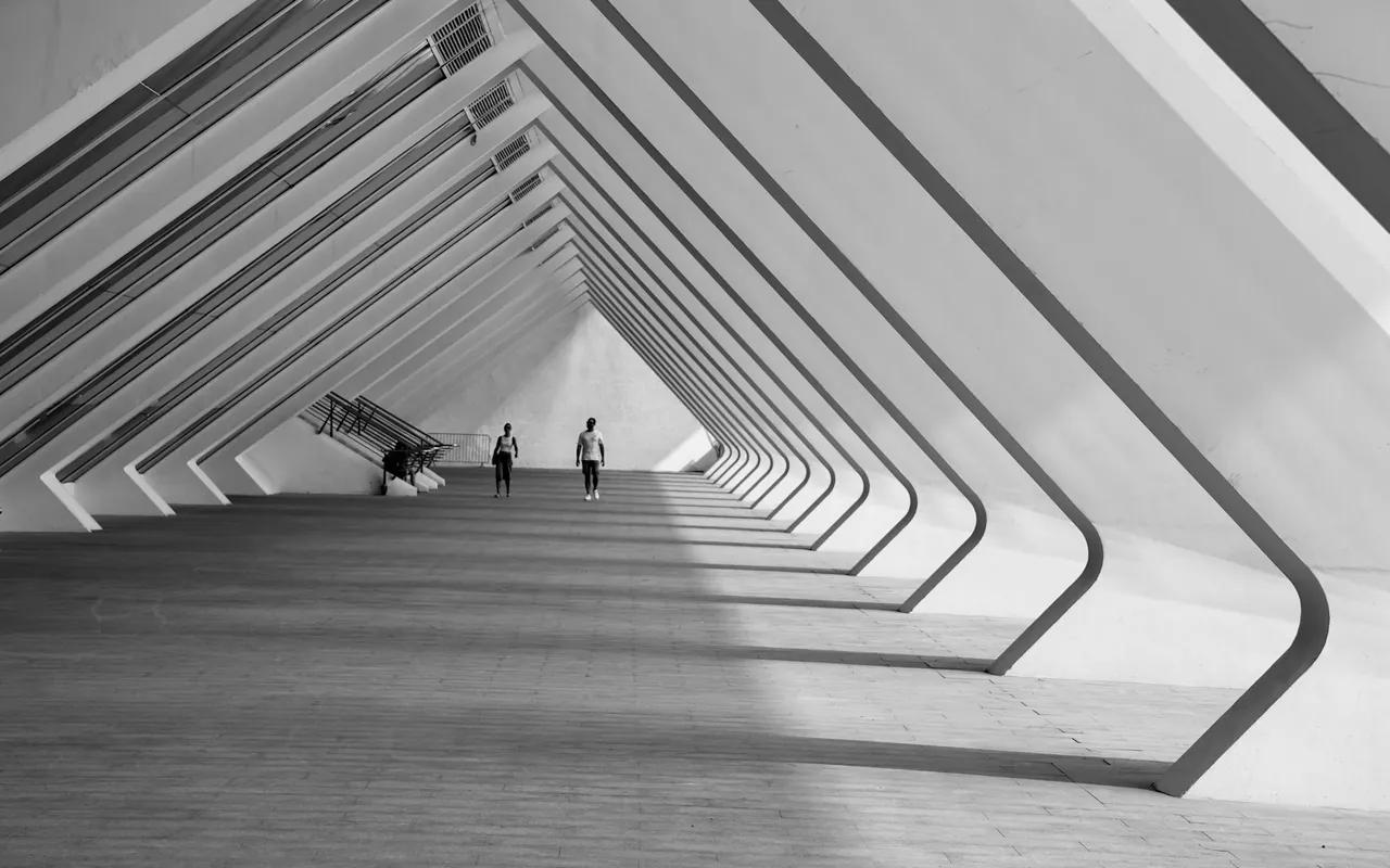 Zwei Menschen unter den weit gespannten, geometrischen Bögen einer modernen Architektur in Valencia.